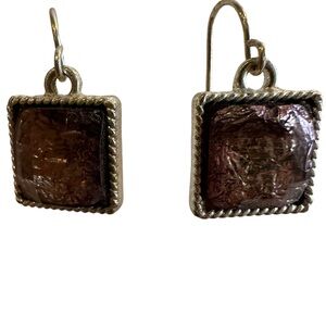 Plum colored square earring surrounded by silver colored metal pierced ears